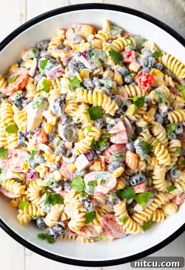 Fiesta Pasta Salad 2 A top down shot of Creamy Southwest Pasta Salad in a white serving bowl, showcasing colorful ingredients.