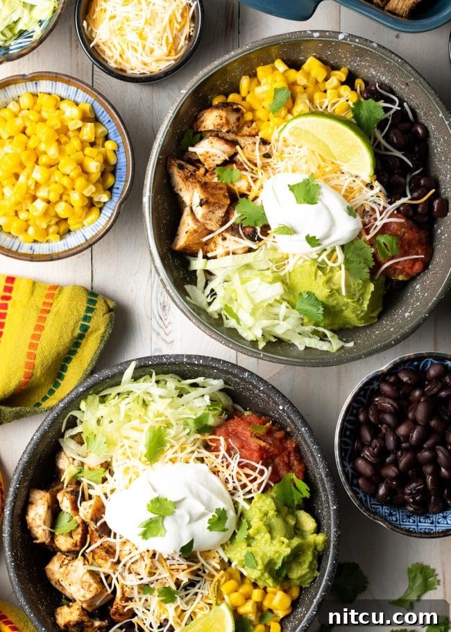 Homemade Chipotle Meal Prep Bowls 11 A vibrant photo of several grilled chipotle chicken burrito bowls, topped with black beans, corn, fresh salsa, and other Southwestern garnishes.