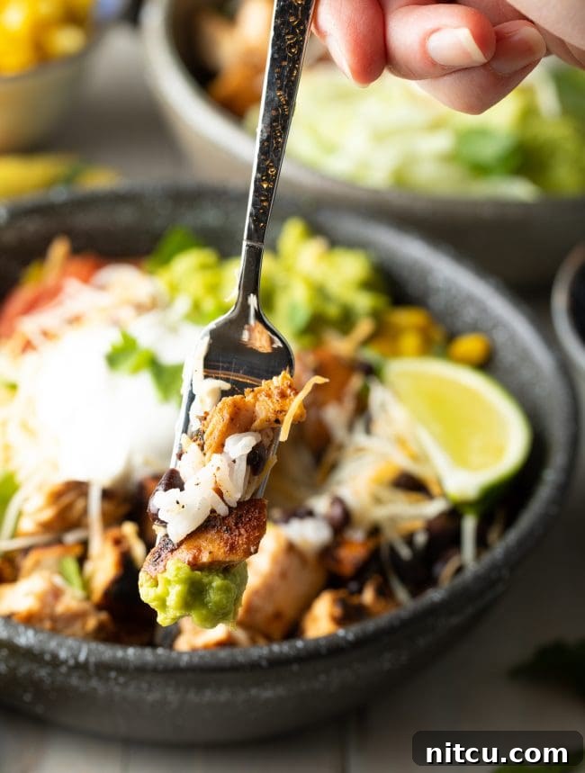 Homemade Chipotle Meal Prep Bowls 4 A spoonful of a homemade chipotle burrito bowl, showing a perfect bite of chicken, rice, and black beans.