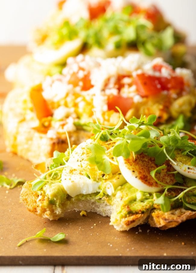 Artfully arranged avocado toast with egg and various toppings, ready to eat