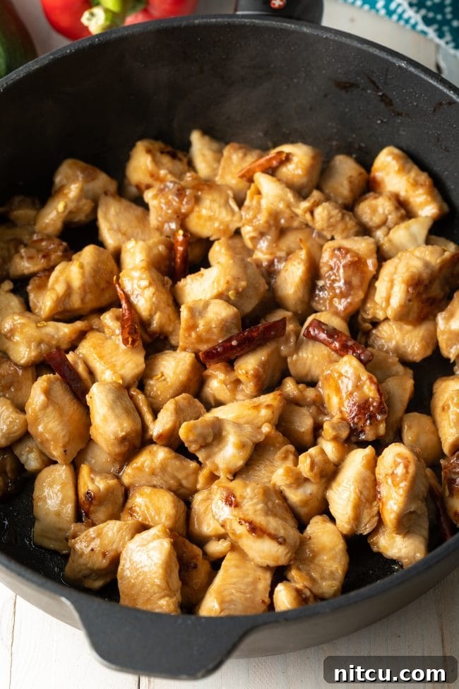 Sichuan Kung Pao Chicken 8 Chopped chicken and red chiles sautéing in a cast iron skillet.