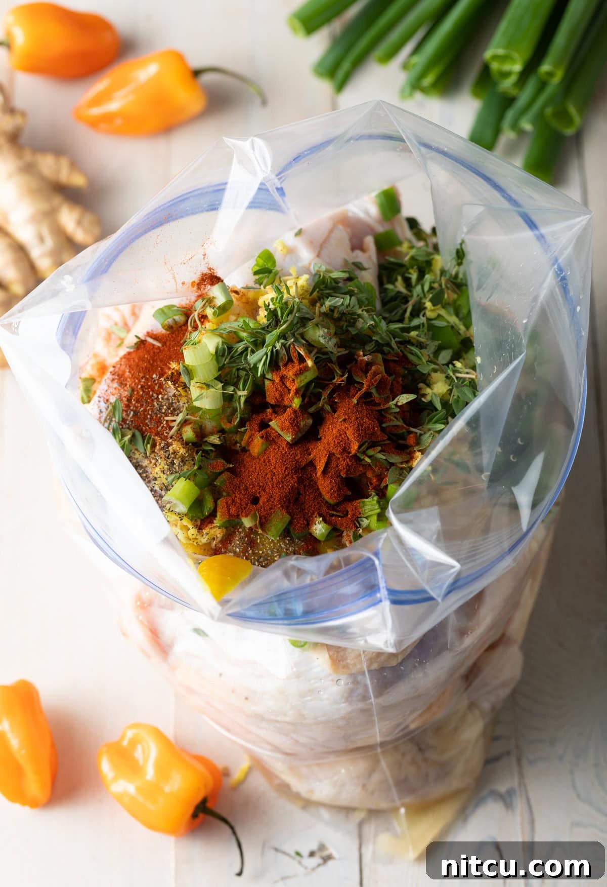 Authentic Jamaican Brown Stew Chicken 5 Zip loc bag filled with ingredients for marinade and pieces of raw chicken.