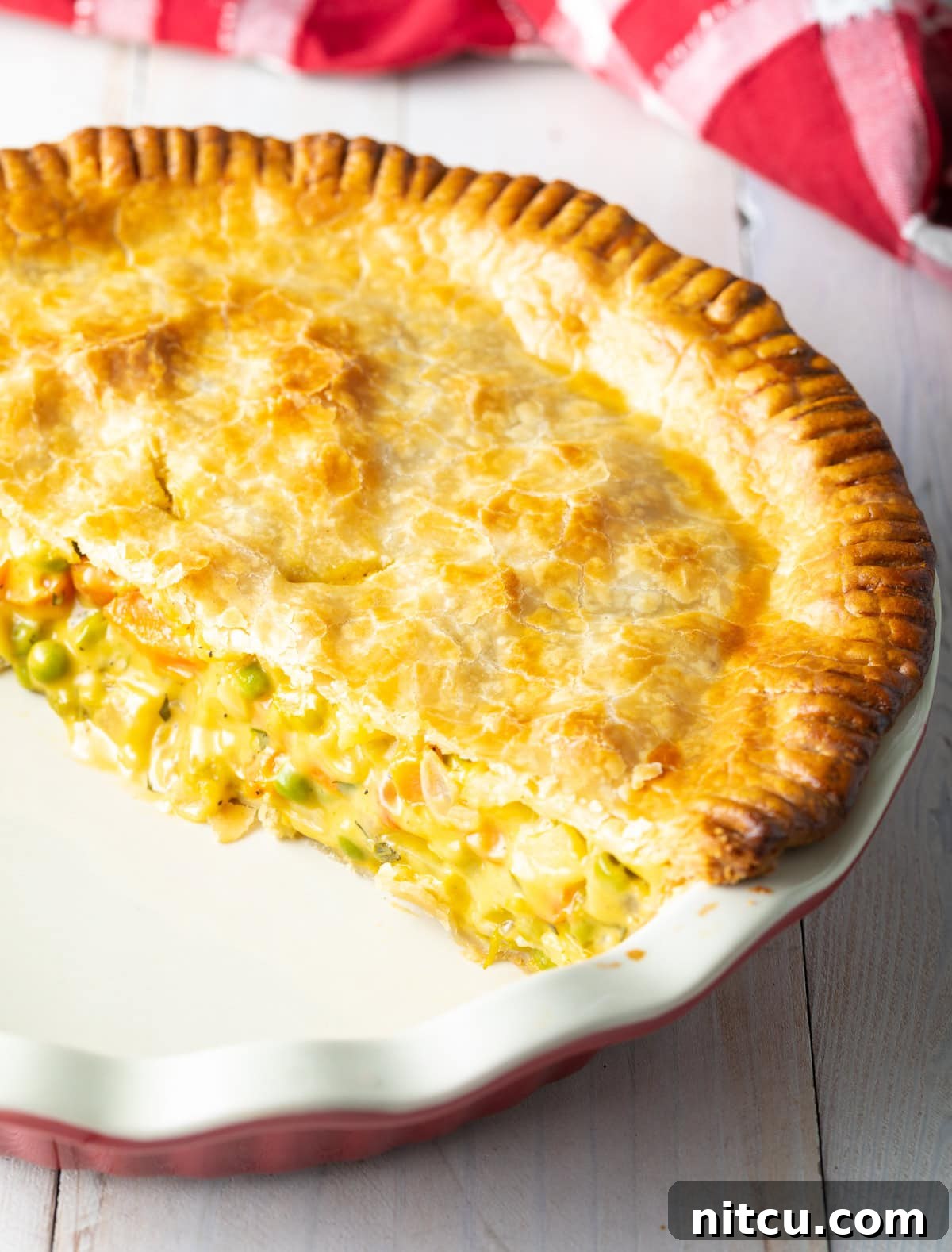 A large slice of cooked veggie pot pie removed from the baking dish, revealing the rich, creamy filling.