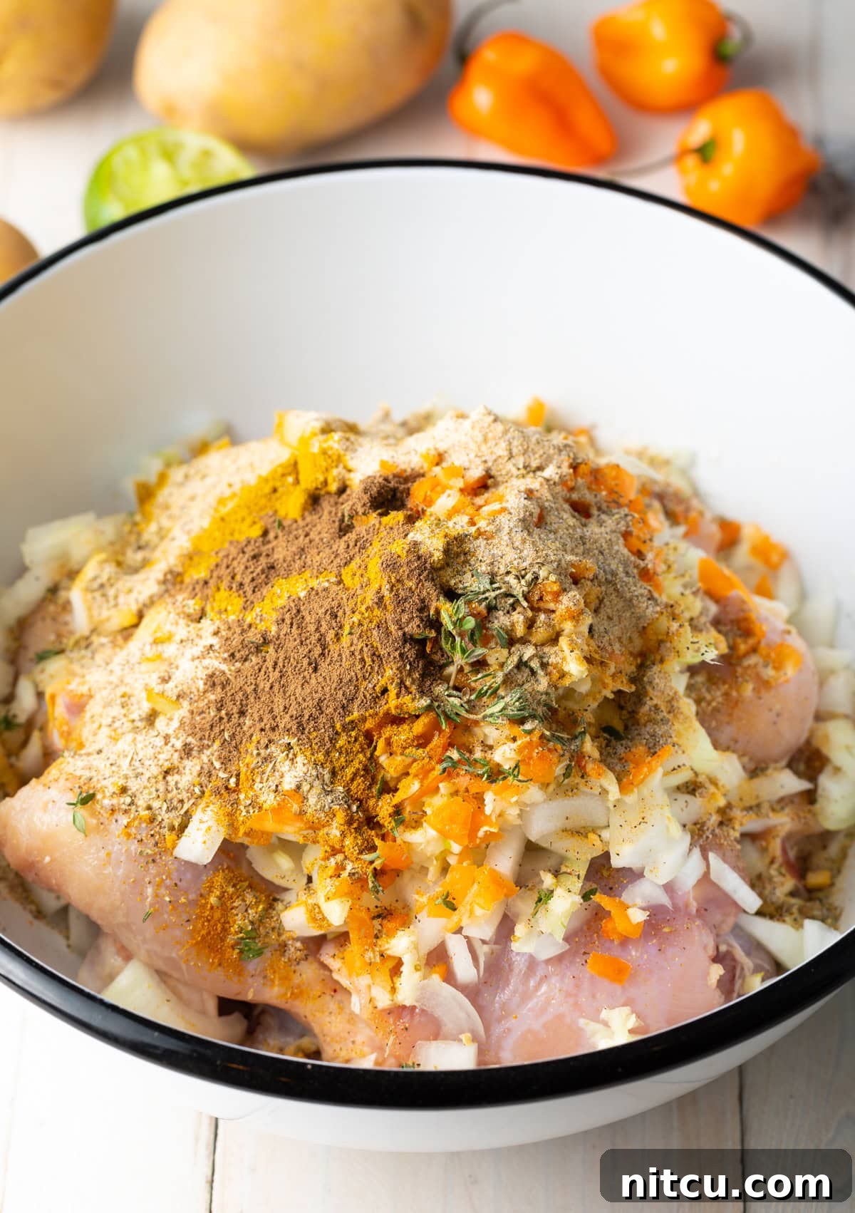 Jamaican Curry Chicken Delights 5 Chicken marinating in a bowl with spices and herbs.