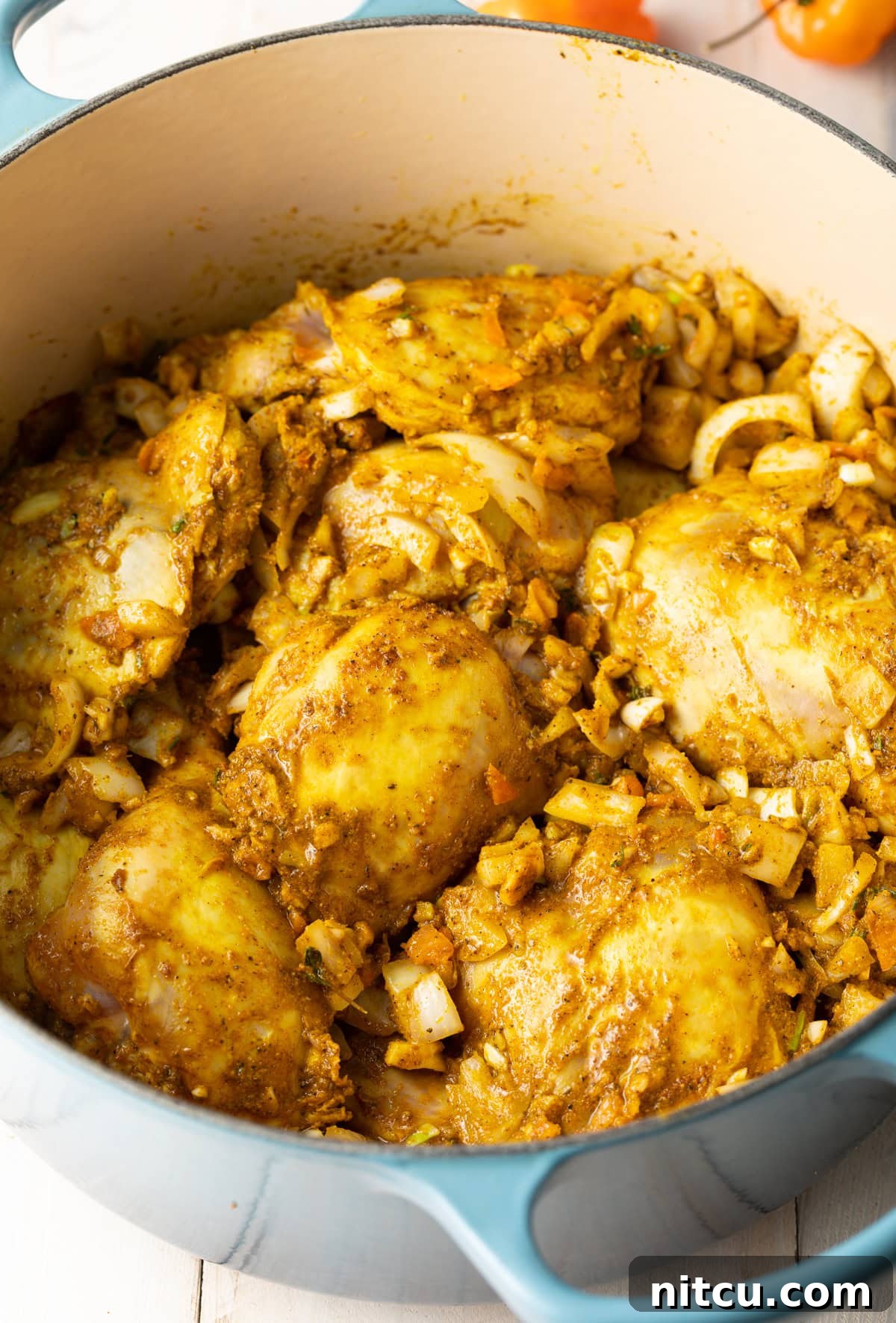 Jamaican Curry Chicken Delights 6 Chicken pieces being browned in a large pot on the stovetop.