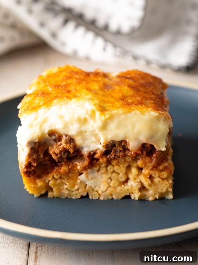 Hearty Greek Pastitsio Casserole 4 Square of Greek lasagna with bucatini pasta and creamy bechamel sauce, on a gray plate.