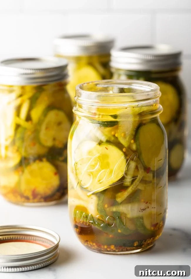 Effortless Homemade Bread & Butter Pickles 2 Opened jar of bread and butter pickles with more jars in the background.