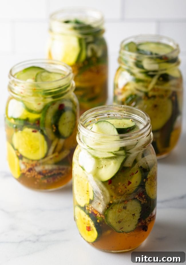 Effortless Homemade Bread & Butter Pickles 11 Four jars of cucumbers and onions with pickling liquid.