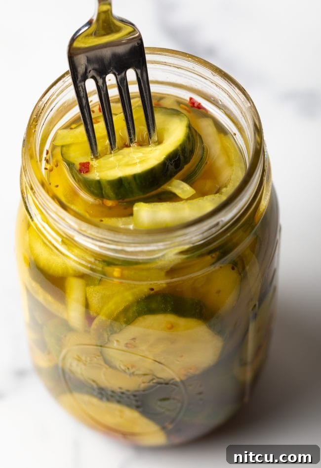 Effortless Homemade Bread & Butter Pickles 4 Using a fork to get a sweet pickle slice from a jar.