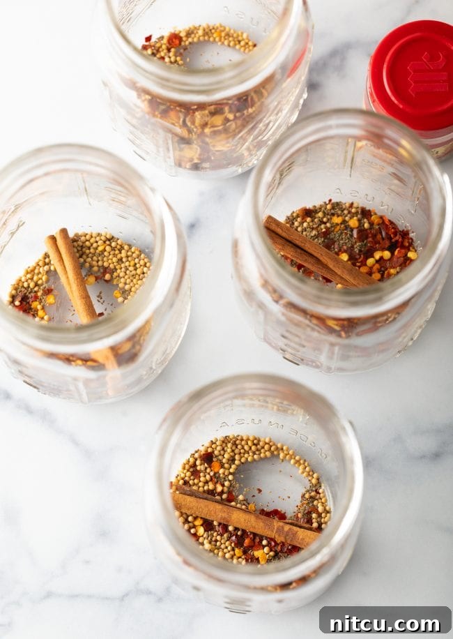 Effortless Homemade Bread & Butter Pickles 8 Four glass jars with cinnamon sticks and mustard seeds.