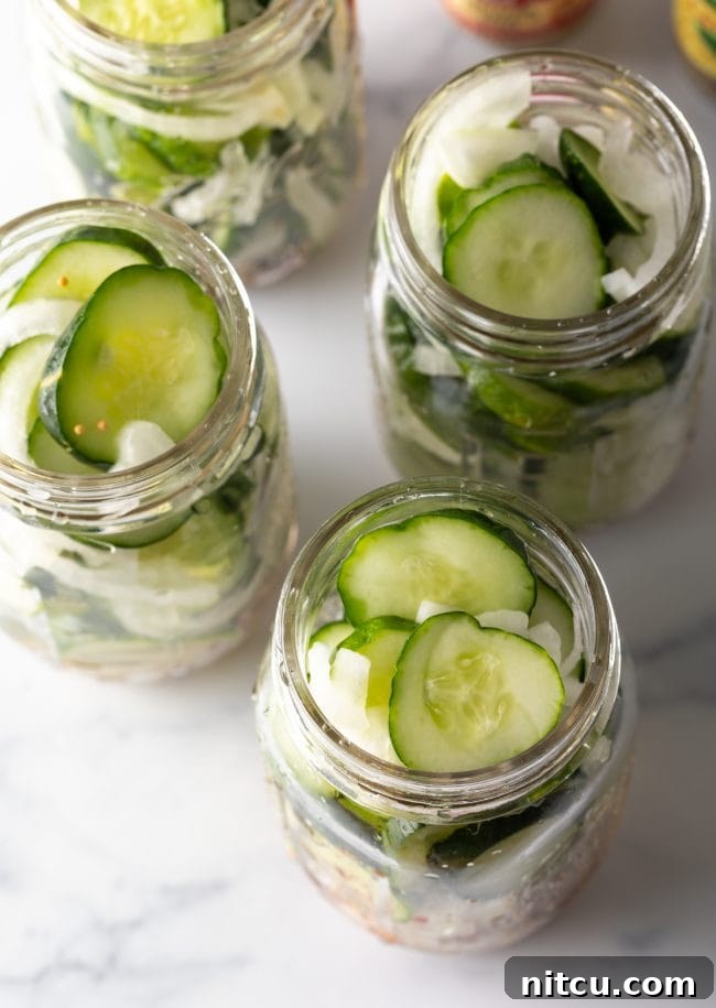 Effortless Homemade Bread & Butter Pickles 9 Four glass jars filled with cucumber slices and white onion.