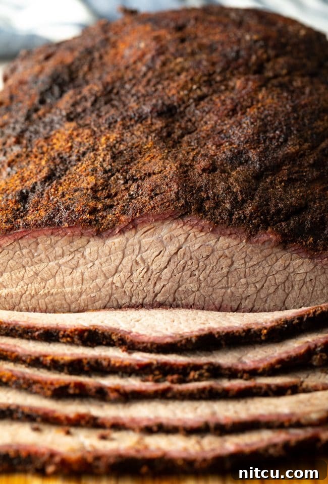 Ultimate Dry-Brined Smoked Brisket 13 Close-up view of perfectly sliced Texas smoked beef brisket, showcasing its tender texture and smoke ring.