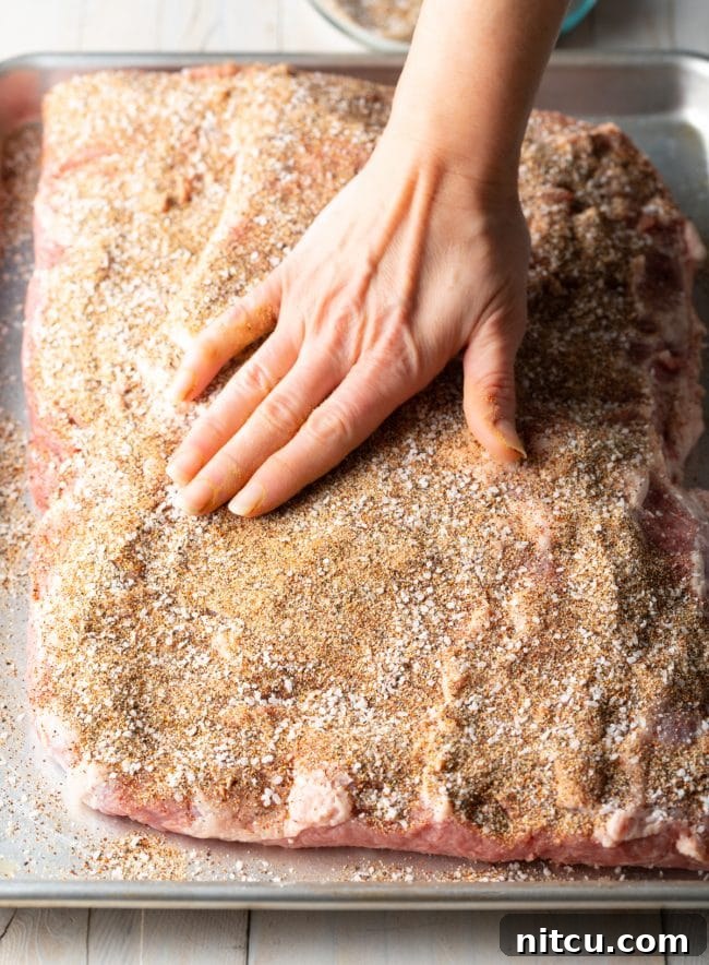 Ultimate Dry-Brined Smoked Brisket 8 A hand rubbing the dry brisket brine spices onto the meat, ensuring even coverage.