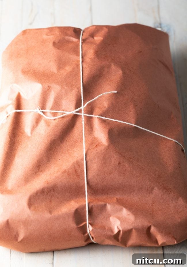 Ultimate Dry-Brined Smoked Brisket 9 Brisket tightly wrapped in pink butcher paper and secured with kitchen twine.