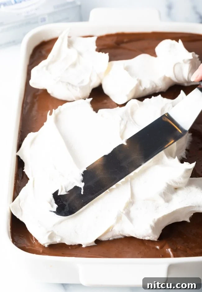 Layered Chocolate Indulgence 13 Spreading the final layer of Cool Whip over the chocolate pudding layer.