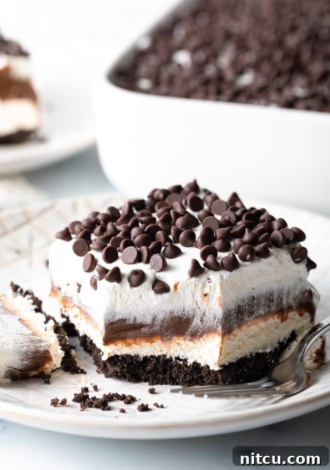 Layered Chocolate Indulgence 5 A slice of No-Bake Chocolate Lasagna with a bite taken out, showing the perfect layering of Oreo crust, cream cheese, chocolate pudding, and whipped topping.