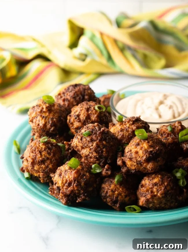 A generous plate of golden-brown Bahamian Conch Fritters, perfectly crispy on the outside, served alongside various savory dipping sauces, ready to be enjoyed as a snack or appetizer.