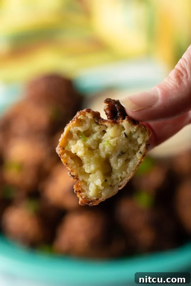 A close-up, cross-section view of a fried conch fritter showing its tender, moist interior with visible pieces of conch and vegetables, indicating perfect doneness.