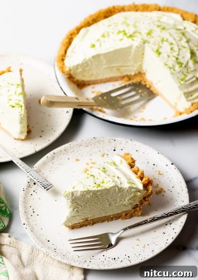 Effortless Key Lime Pie 4 Multiple slices of chilled frozen key lime pie arranged on individual plates in the foreground, with the full, uncut pie visible in the background, creating an enticing display of this refreshing dessert.