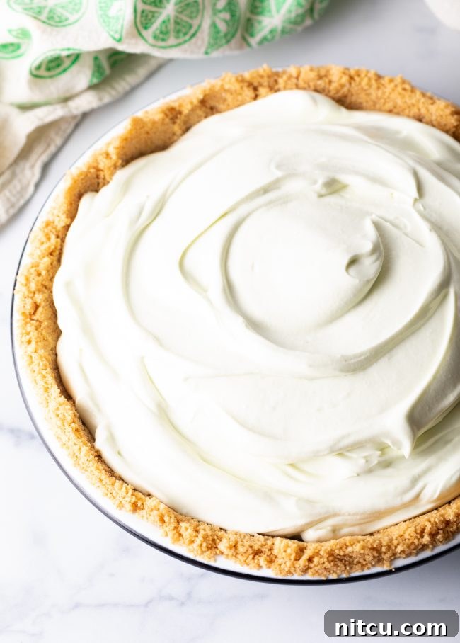 Effortless Key Lime Pie 10 The fluffy, vibrant key lime pie filling has been perfectly poured and smoothed into a crisp graham cracker crust, showcasing the layers before freezing.