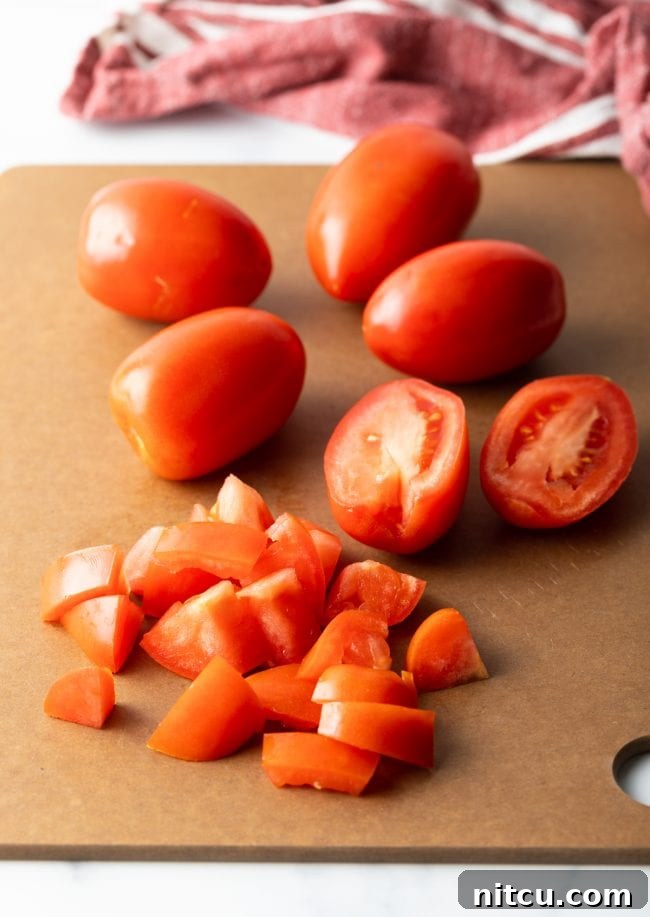Fresh, ripe tomatoes neatly chopped on a wooden cutting board, ready for the jam-making process.