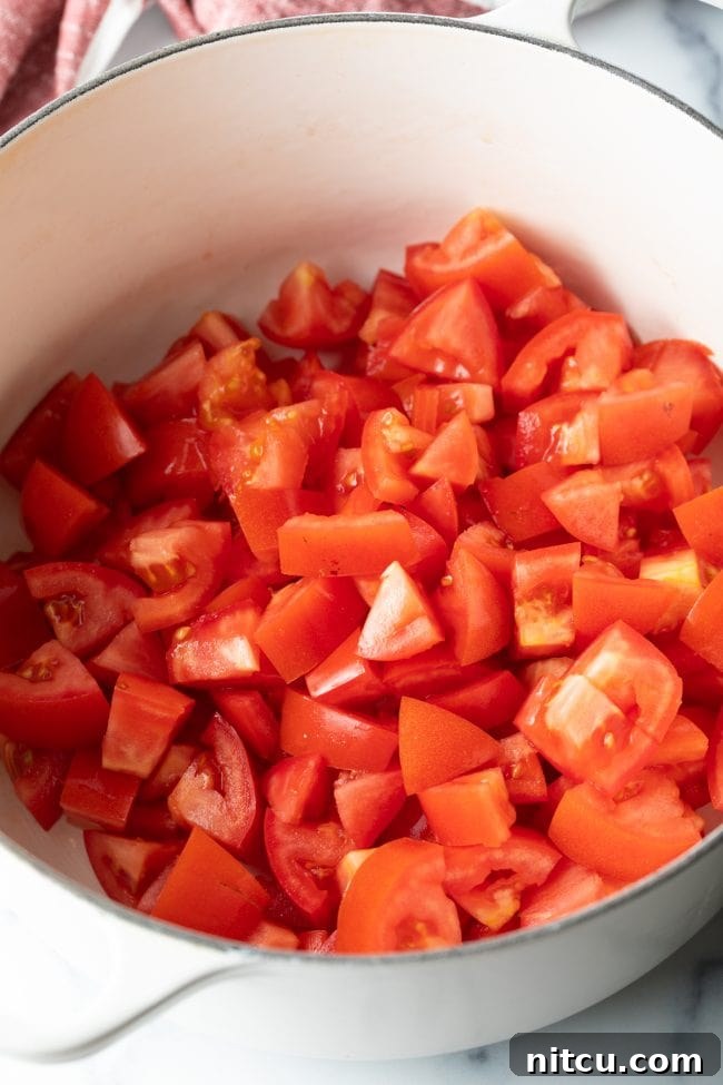 Chopped tomatoes placed in a sturdy pot, awaiting the addition of other jam ingredients.