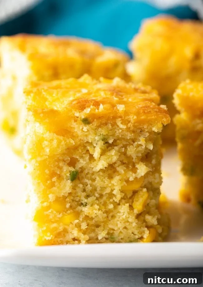 Zesty Jalapeno Cheddar Cornbread 2 Close-up slice of fluffy jalapeno cheddar cornbread, showcasing its moist texture and cheesy interior.
