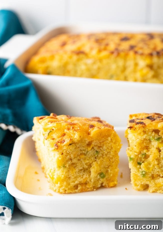 Zesty Jalapeno Cheddar Cornbread 13 Side view of jalapeno cornbread squares filled with chopped peppers and topped with melted cheese, showcasing its rich texture.