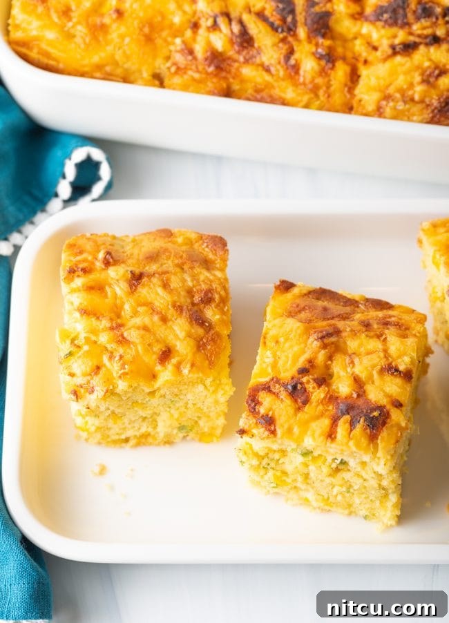 Zesty Jalapeno Cheddar Cornbread 5 Overhead view of perfectly baked squares of jalapeno cheddar cornbread arranged on a white platter.
