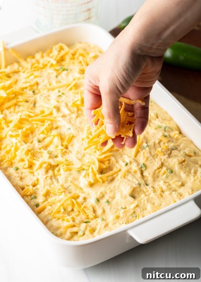 Zesty Jalapeno Cheddar Cornbread 10 Cornbread batter scooped into a baking dish, ready for the final cheese sprinkle.