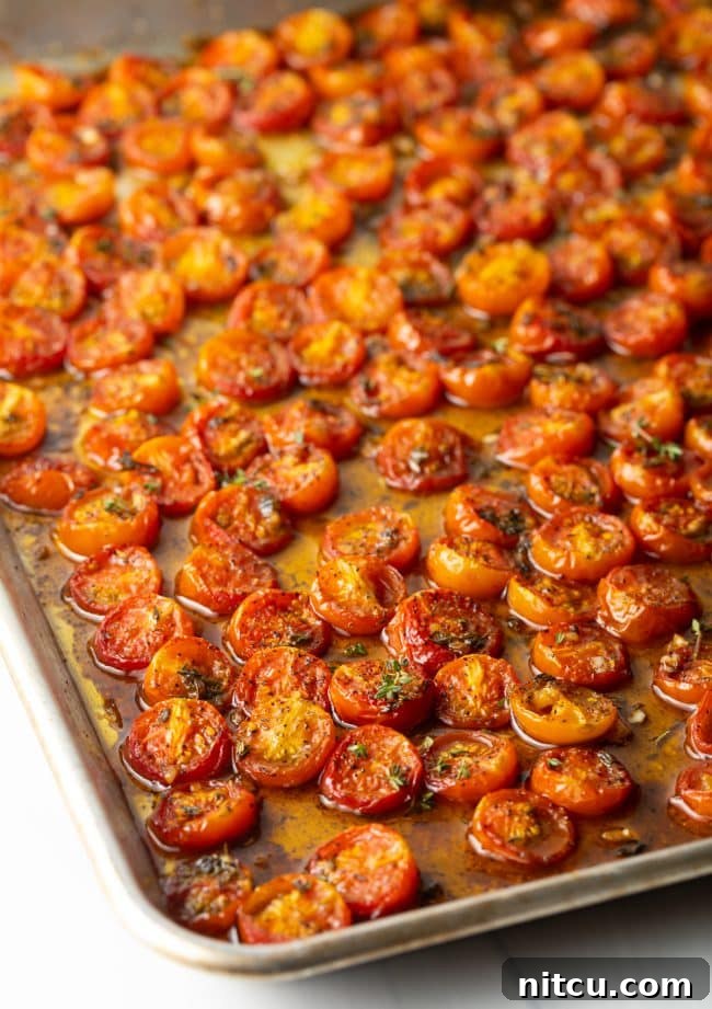 Oven-Kissed Cherry Tomatoes 2 Roasted cherry tomatoes on a baking sheet, glistening with balsamic glaze.