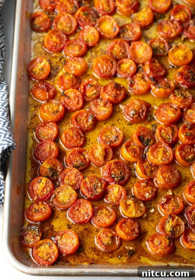 Oven-Kissed Cherry Tomatoes 12 Overhead view of cherry tomatoes roasting in a pan, bubbling with juices and balsamic glaze.