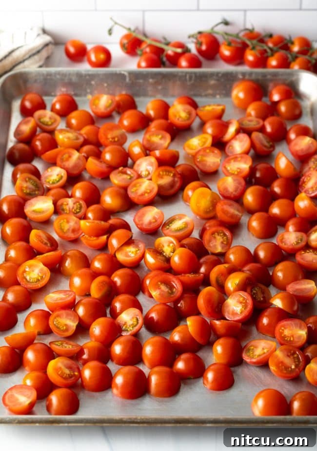 Oven-Kissed Cherry Tomatoes 5 Fresh halved cherry tomatoes arranged on a baking sheet.