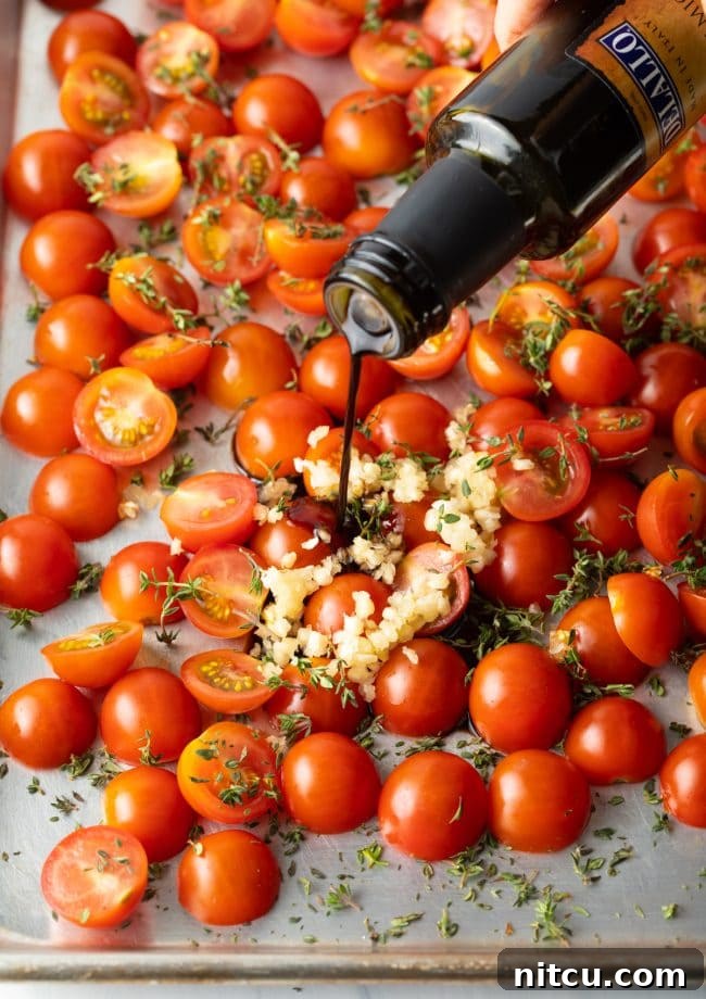 Oven-Kissed Cherry Tomatoes 6 Pouring rich balsamic vinegar over a bed of cherry tomatoes on a baking pan.