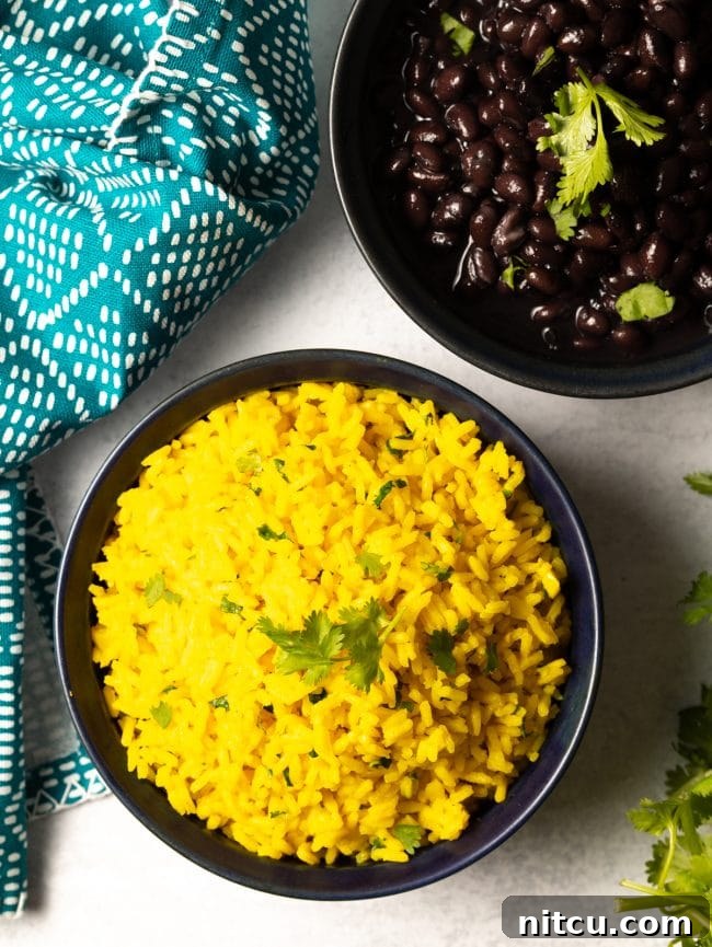 Overhead view of a bowl of vibrant yellow rice served alongside hearty black beans.