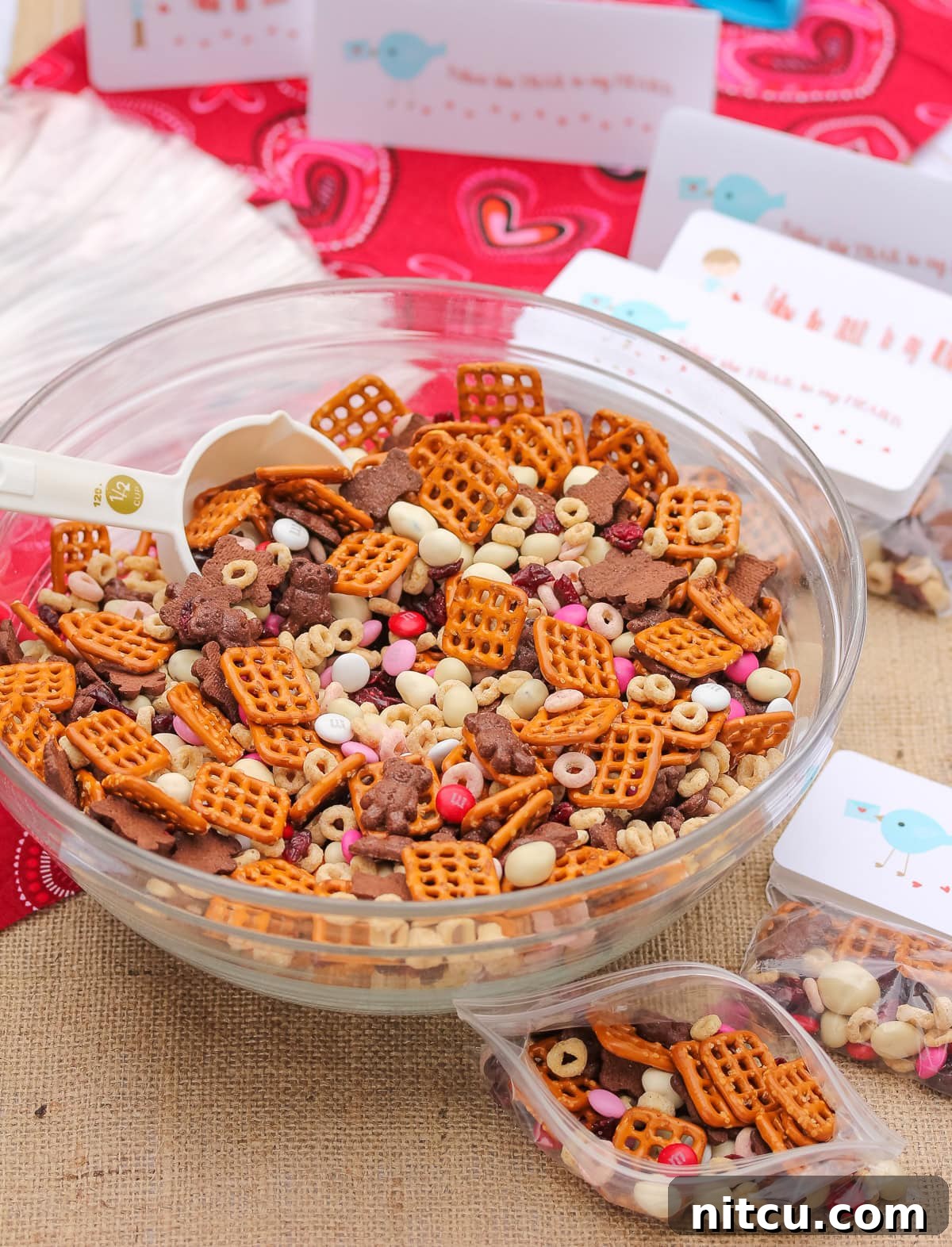 homemade-trail-mix homemade trail mix in a mixing bowl for Valentine's day with gift bags and tags next to it.