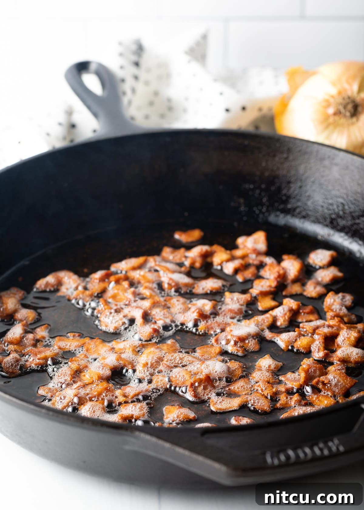 Braised Chicken Delight 5 Close-up of chopped bacon sizzling and browning in a cast iron skillet.