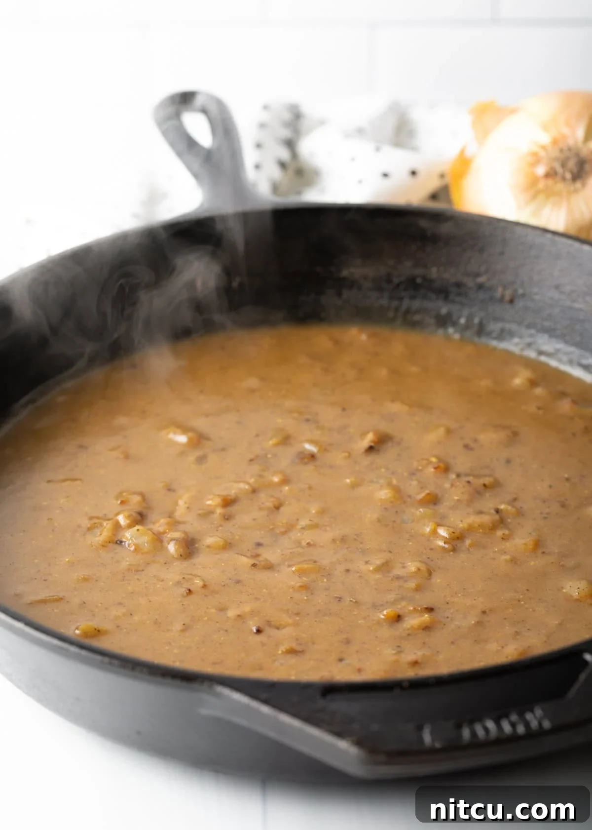 Braised Chicken Delight 7 Rich, brown gravy simmering and thickening in a cast iron skillet on the stovetop.