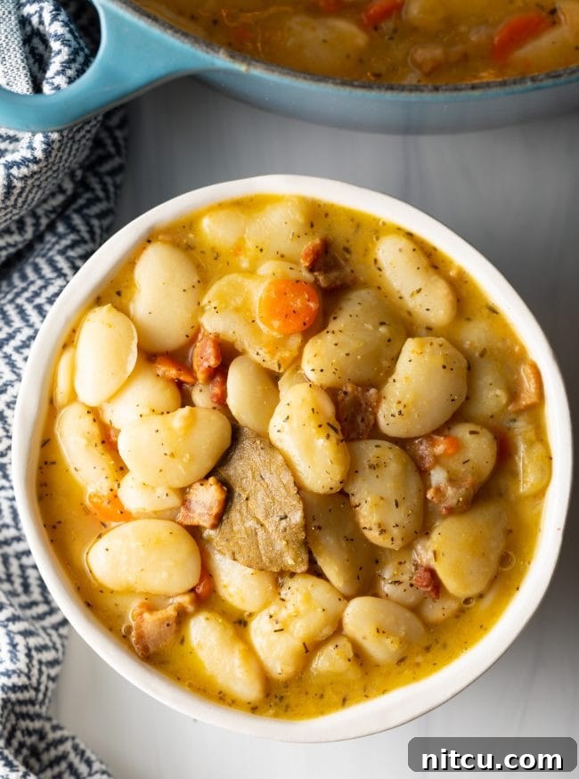 Final overhead view of a rustic bowl filled with perfectly cooked butter beans, garnished with crispy bacon, ready to be served as a comforting Southern meal.