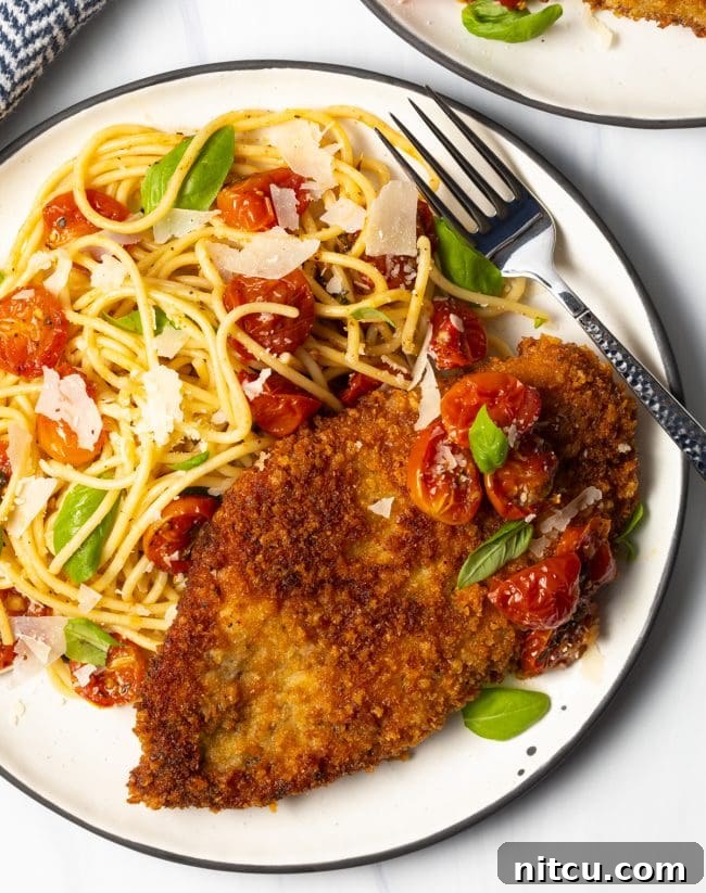 Crispy Italian Chicken Cutlets 9 overhead view of finished plate with crunchy Panko Italian breasts cut thin, on a plate with spaghetti and cherry tomato sauce on the side