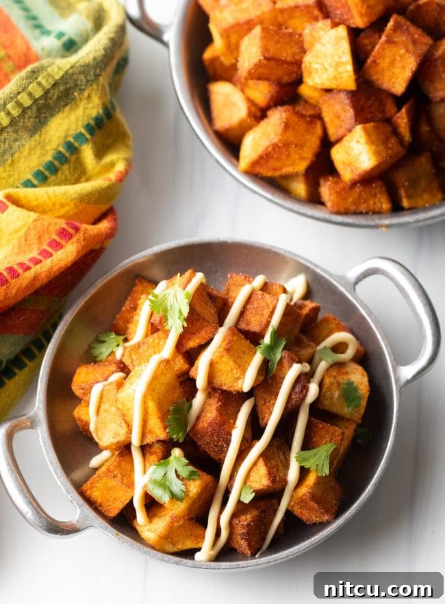 Fiesta Potatoes 11 Overhead view of two bowls of Mexican fried potatoes with creamy aioli and chopped cilantro garnish