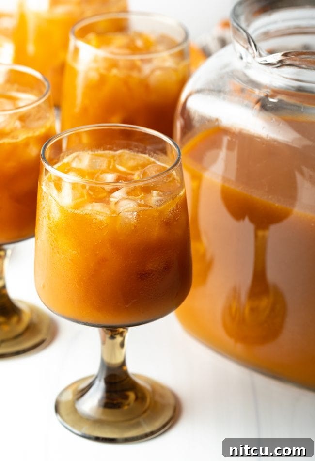 Hogwarts Pumpkin Juice 4 glass of iced juice with pumpkin puree and fruit over ice, next to a pitcher of juice
