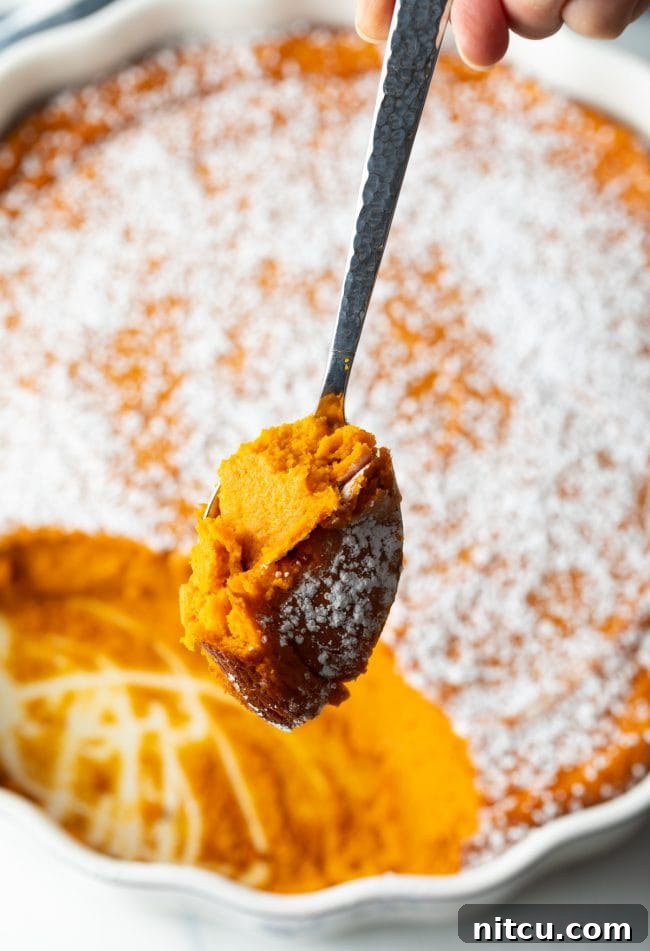 Golden Carrot Cloud 10 spoon with scoop of carrot souffle over full casserole in background