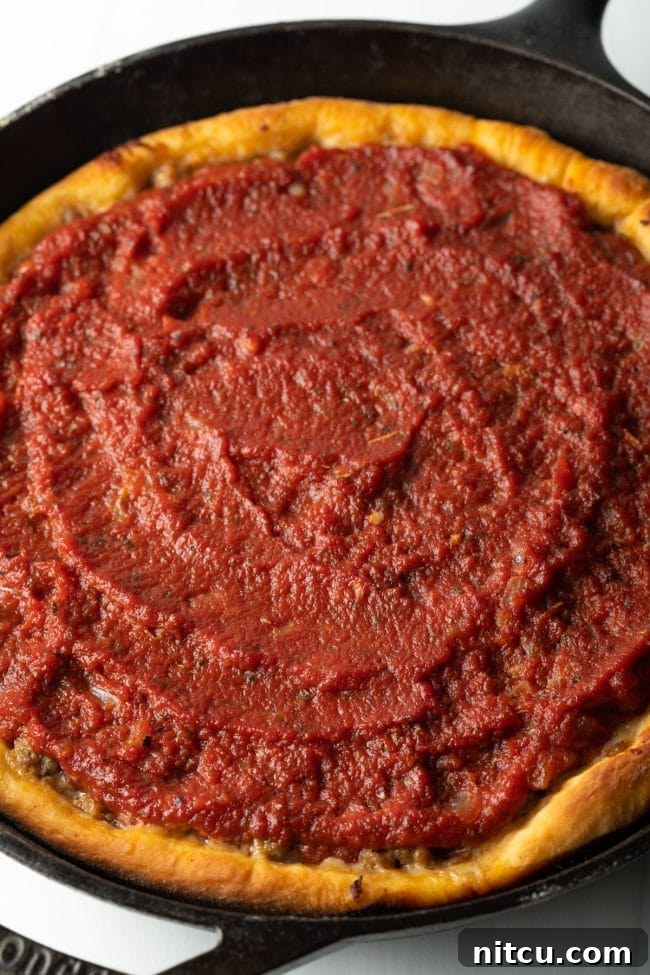 Iron-Clad Deep Dish Delight 8 A glorious top-down view of the freshly baked deep dish pizza, showcasing its rich red tomato sauce and perfectly golden crust edges, straight from the oven.