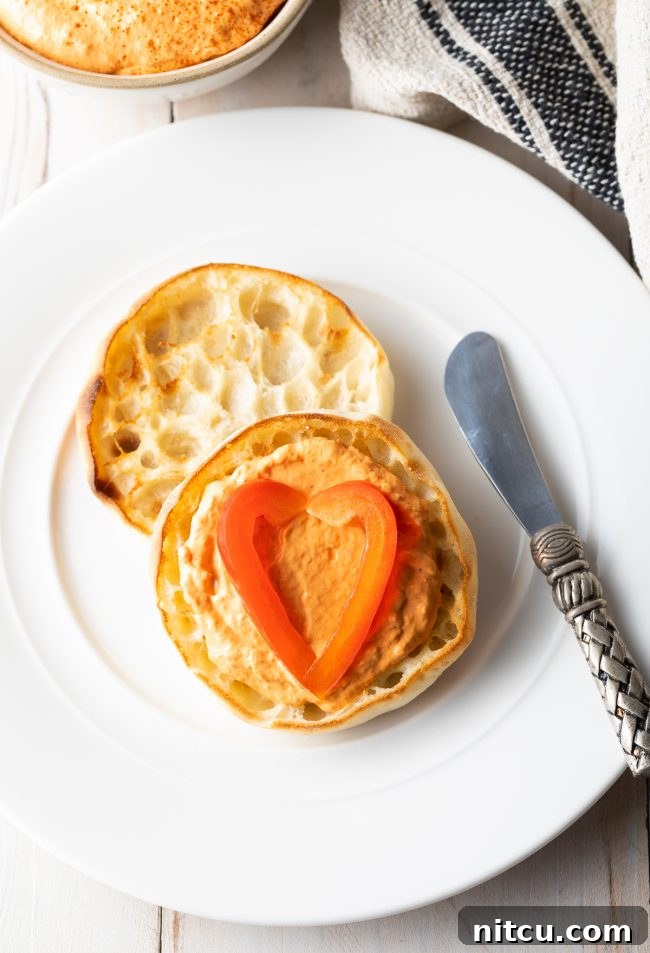 Easy-Roasted-Red-Pepper-Sauce Roasted Red Pepper dip on an English muffin with a butter knife next to it.