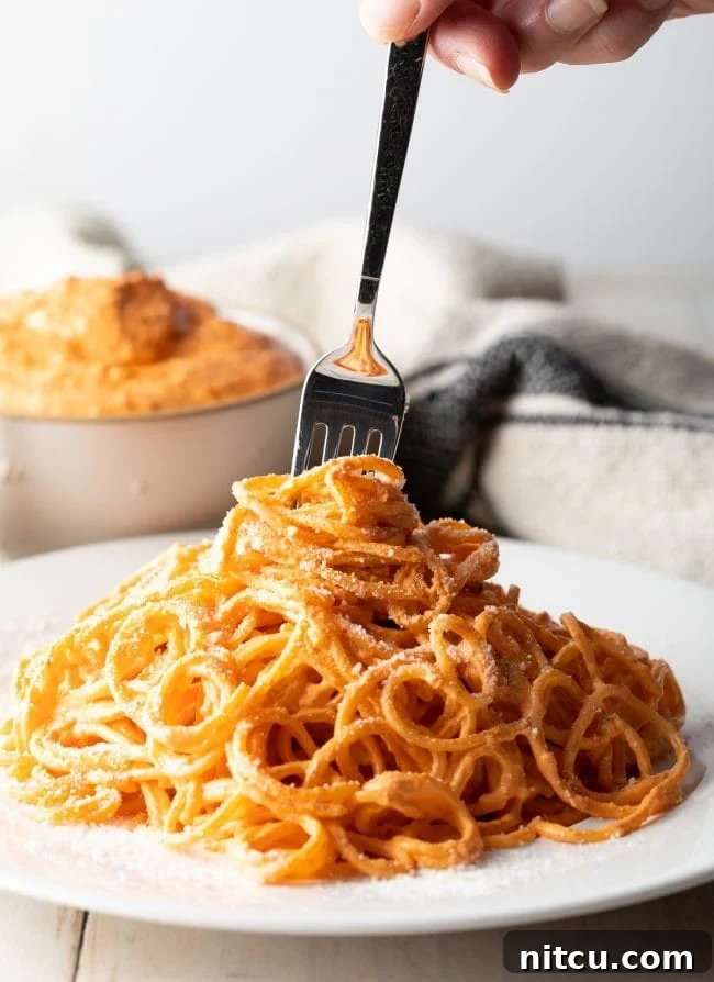 Roasted-Red-Pepper-Sauce Fork swirling around some noodles coated in roasted red pepper sauce.