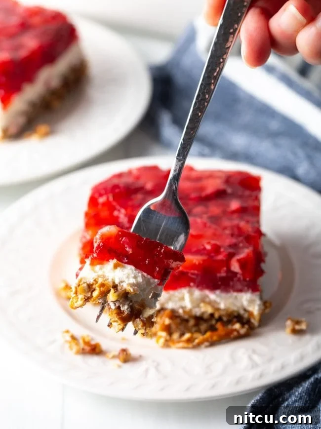 Sweet Strawberry Pretzel Delight 14 A fork holding a bite of strawberry pretzel dessert salad, showing the distinct layers close to the camera.