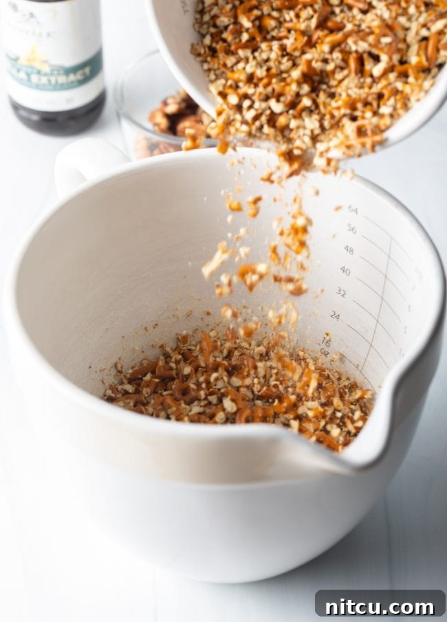 Sweet Strawberry Pretzel Delight 6 Crushed pretzels being added to a large measuring cup, showing their texture.