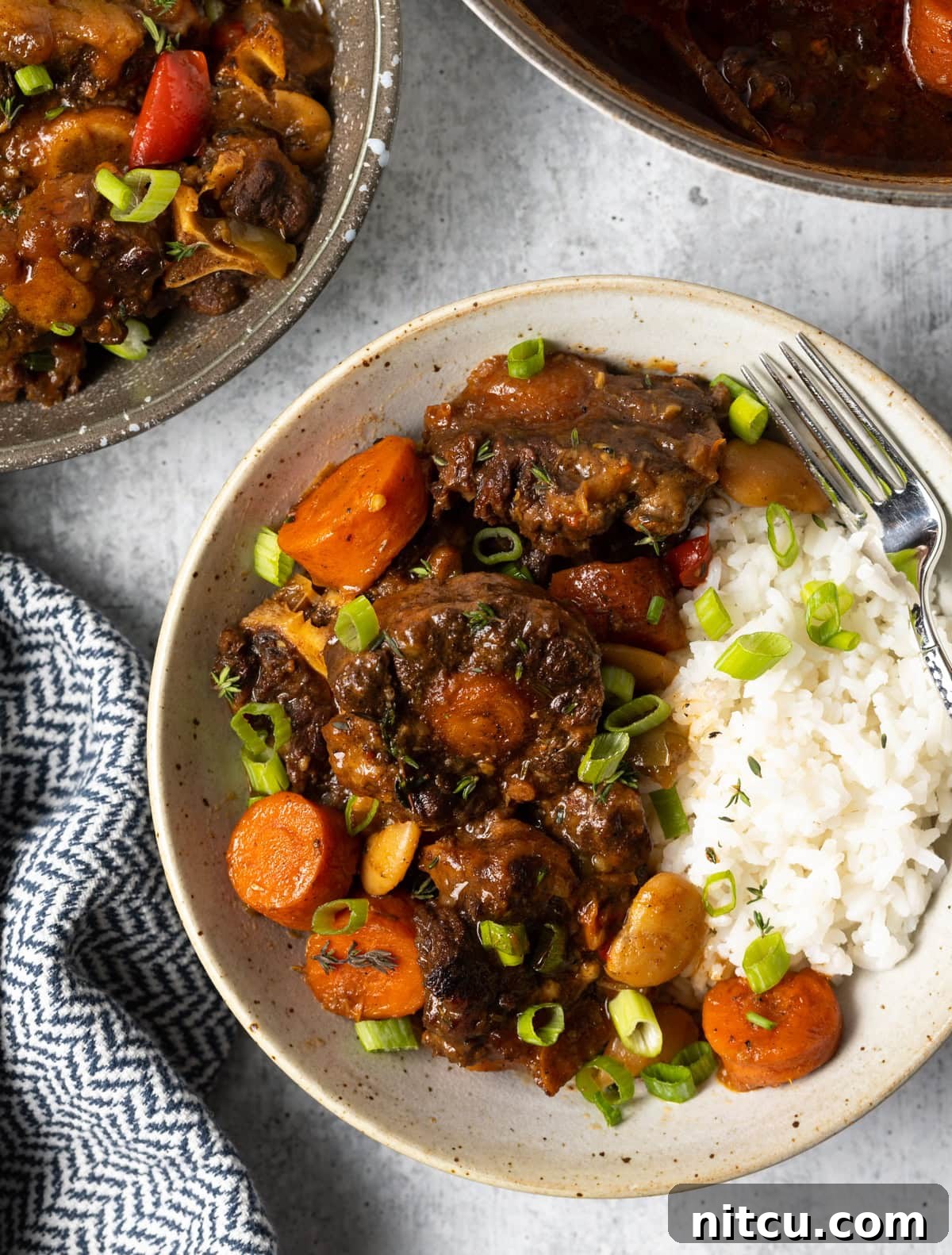 Overhead shot of Jamaican Oxtail Stew Recipe in bowls, garnished with fresh herbs.