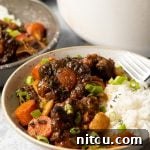 White bowl with Jamaican oxtail and beans stew and white rice.